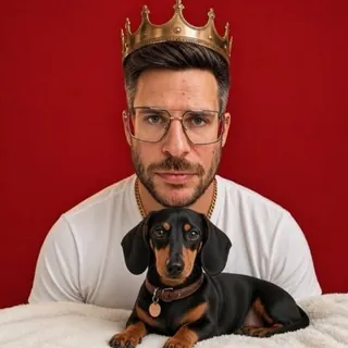 Max Fischer with a golden crown and his dachshund in front of a red wall.